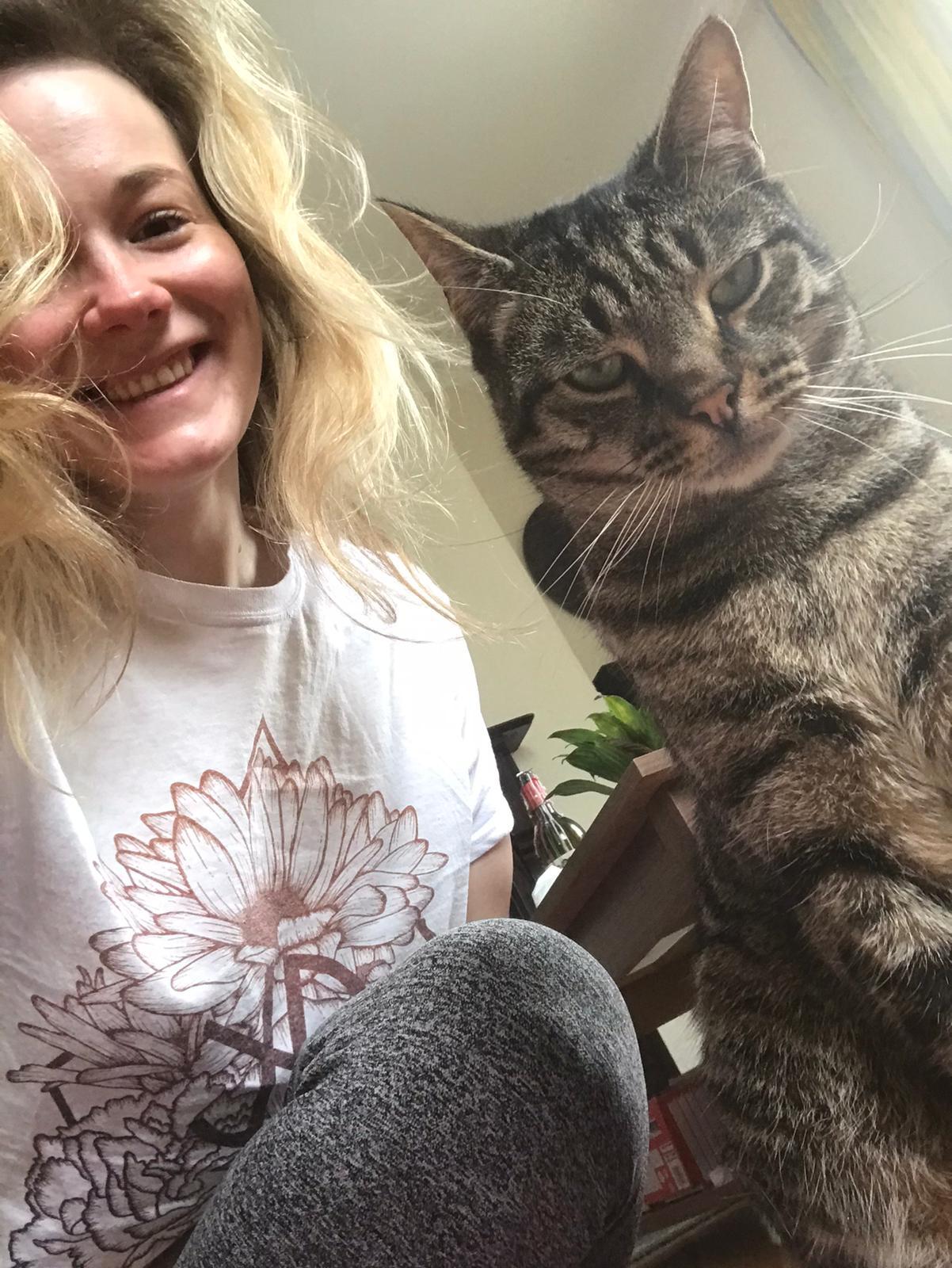 Nou smiling beside one of the farm’s tabby cats.